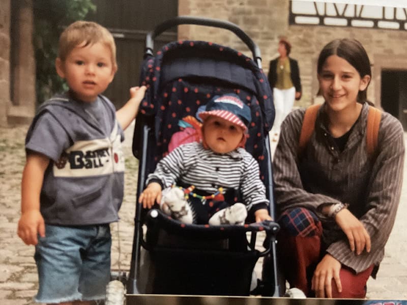 Kleinkinder mit Kinderwagen und älteres Mädchen bei Geburtstagsparty in historischer Altstadt.