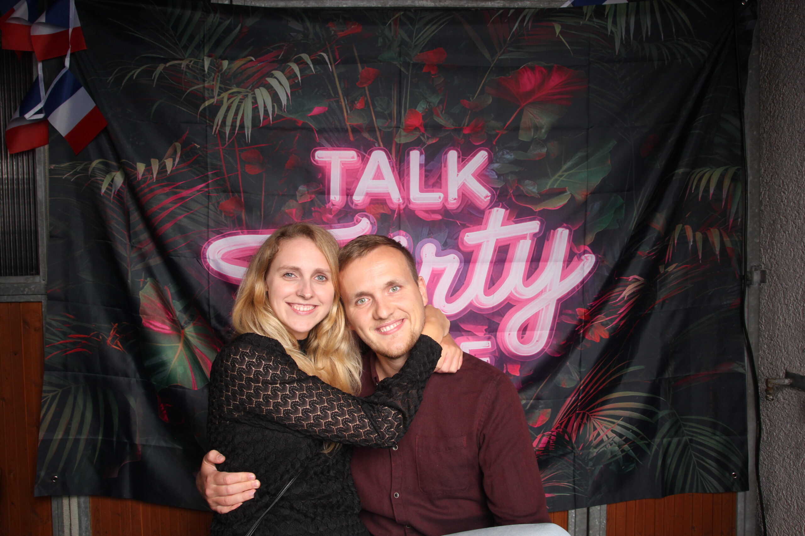 Liebevolle Momentaufnahme bei einer Geburtstagsparty anlässlich Jannik's 30. Geburtstag, mit einer glücklichen Gruppe vor einem bunten, neonbeleuchteten Partyhintergrund.