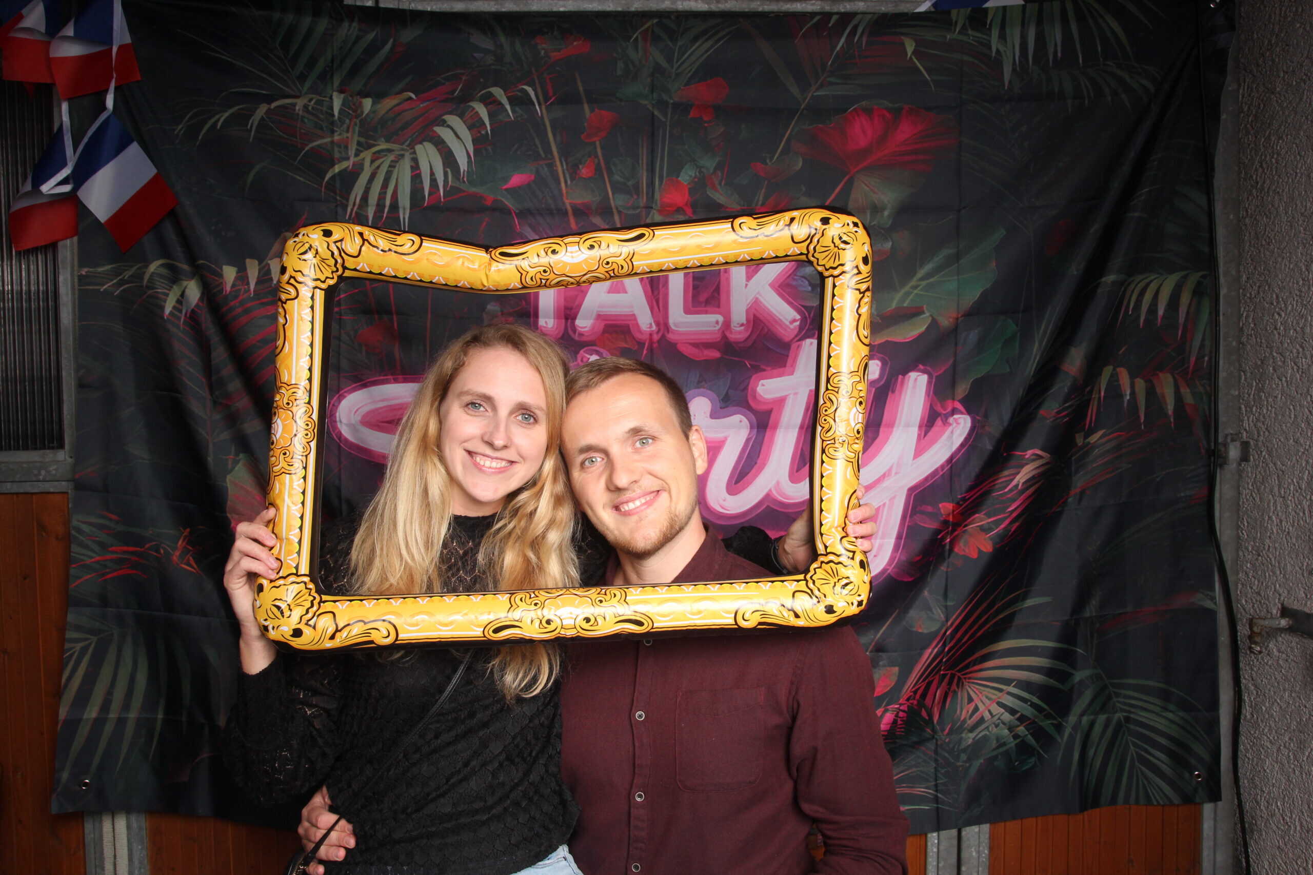 Fröhliches Paar bei Geburtstagsfeier mit Fotohintergrund und Dekoration, perfekte Party für 30. Geburtstag, glückliche Momente feiern.