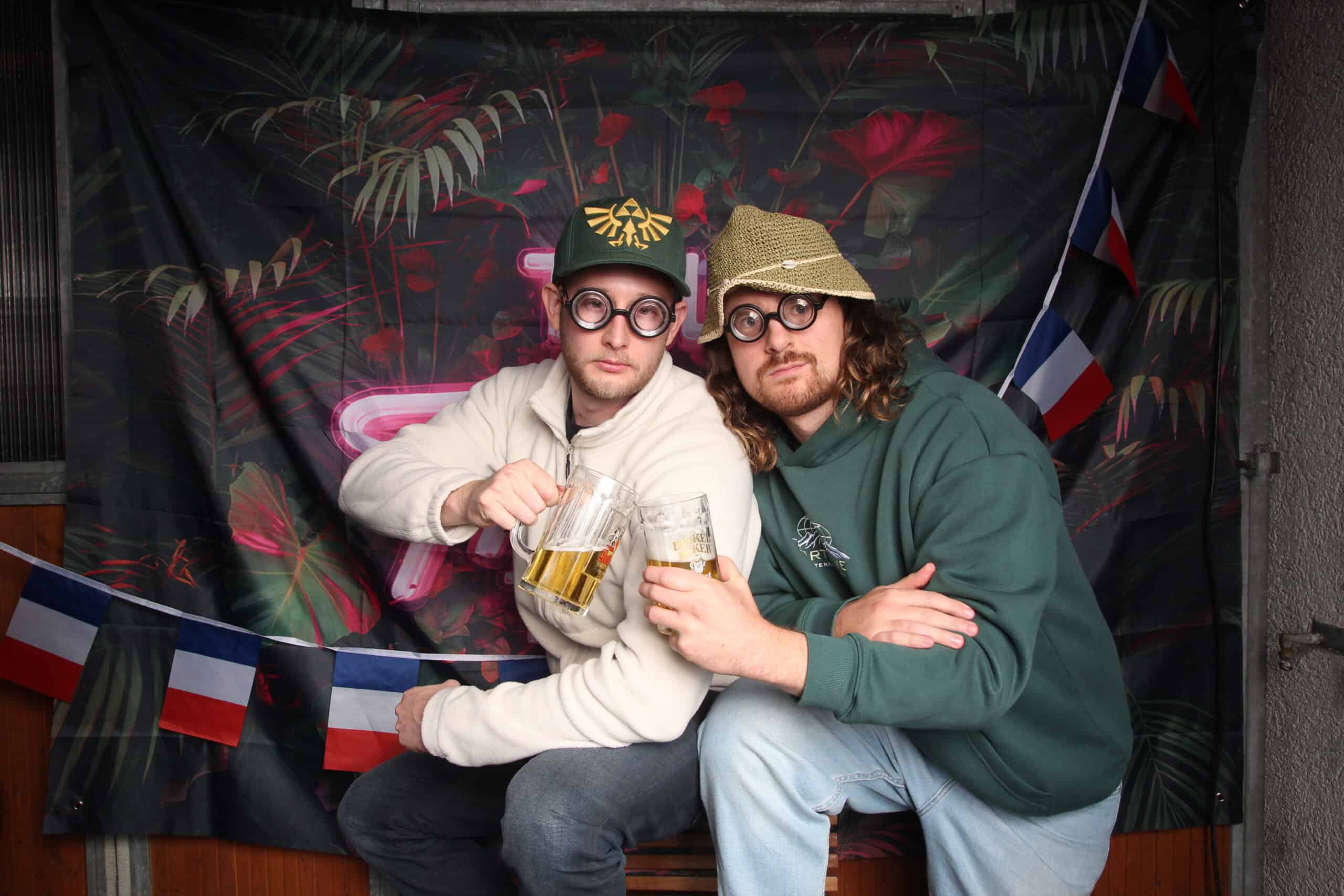 Fröhliche Freunde beim Geburtstag mit Bier, Berliner Mauer- und Flaggen-Dekoration, Spaß und Feierlaune.