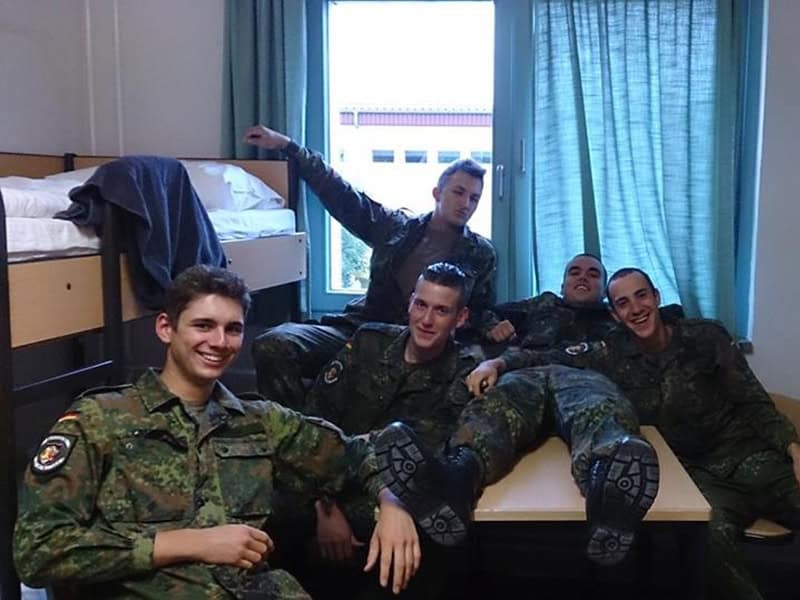Junge Soldaten feiern den 30. Geburtstag, entspannt im Jugendzimmer mit Freunden in militärischer Kleidung.