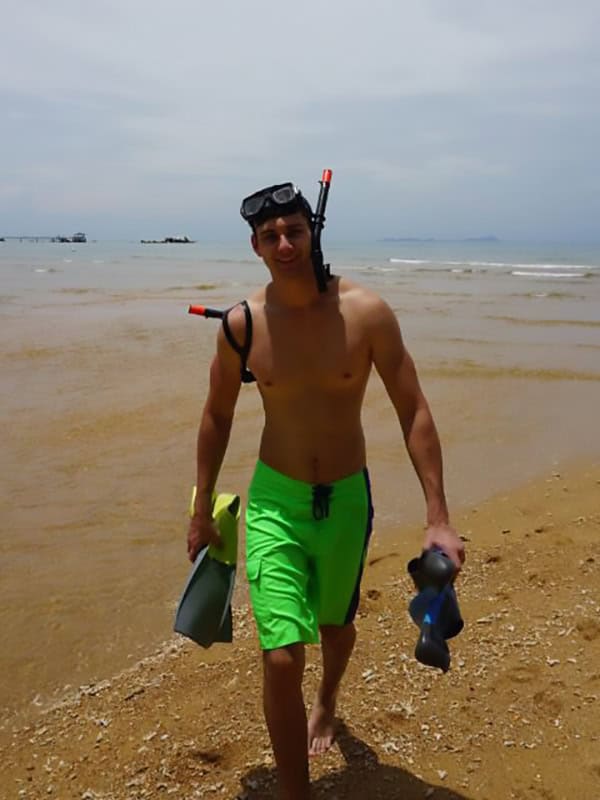 Taucher am Strand, jung, hübsch, dunkle Haare, trägt grüne Shorts, Schnorchel, Flossen, perfekte Urlaubsstimmung, sommerlich, relaxen Ärmel-lose Badesachen, Wasser, Sonne, Urlaub, Meeresnähe, Freizeit, gute Laune.