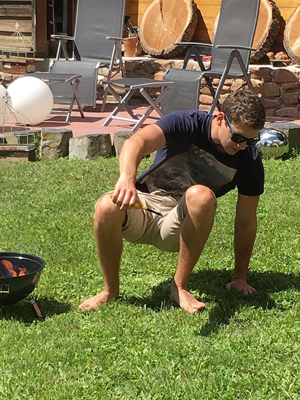 Feuergrill im Garten, junge Person in Pose, Sonne, Freizeit, Gartenparty, gemütliches Outdoor-Event, Sommer.