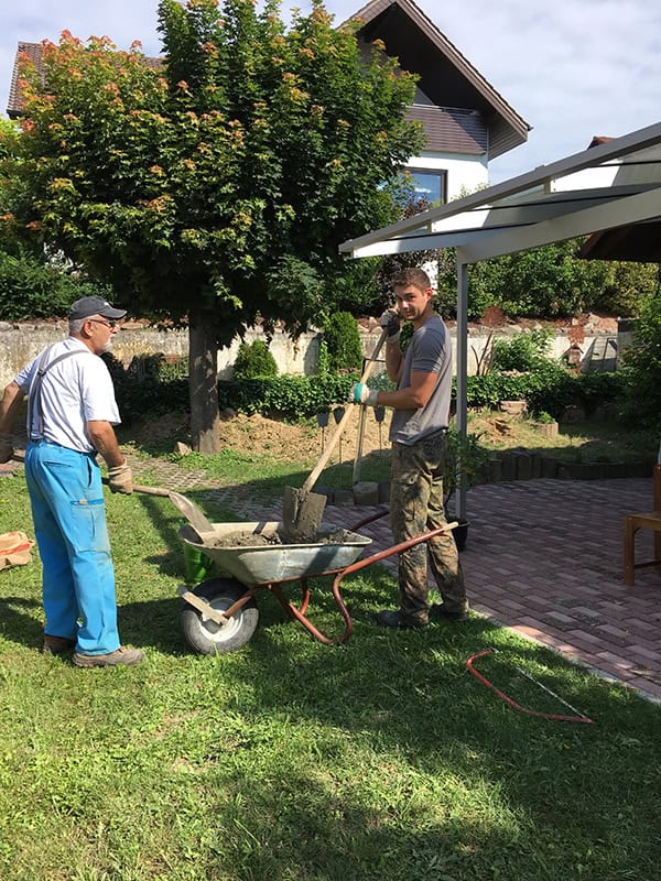 Fensterputzer bei der Arbeit im Garten, fröhliche Stimmung und sonniges Wetter, Service für zuhause.