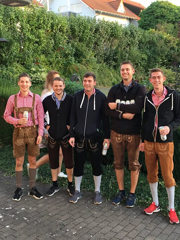 Fröhliche Männer in traditionellen Lederhosen bei einem Oktoberfest-Event.