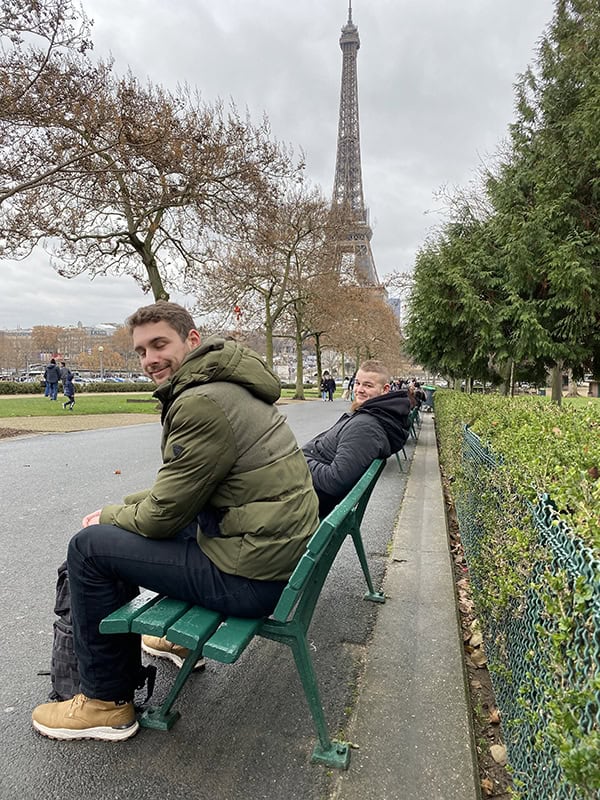 2. Herren sitzen auf Parkbank mit Eiffelturm im Hintergrund in Paris.