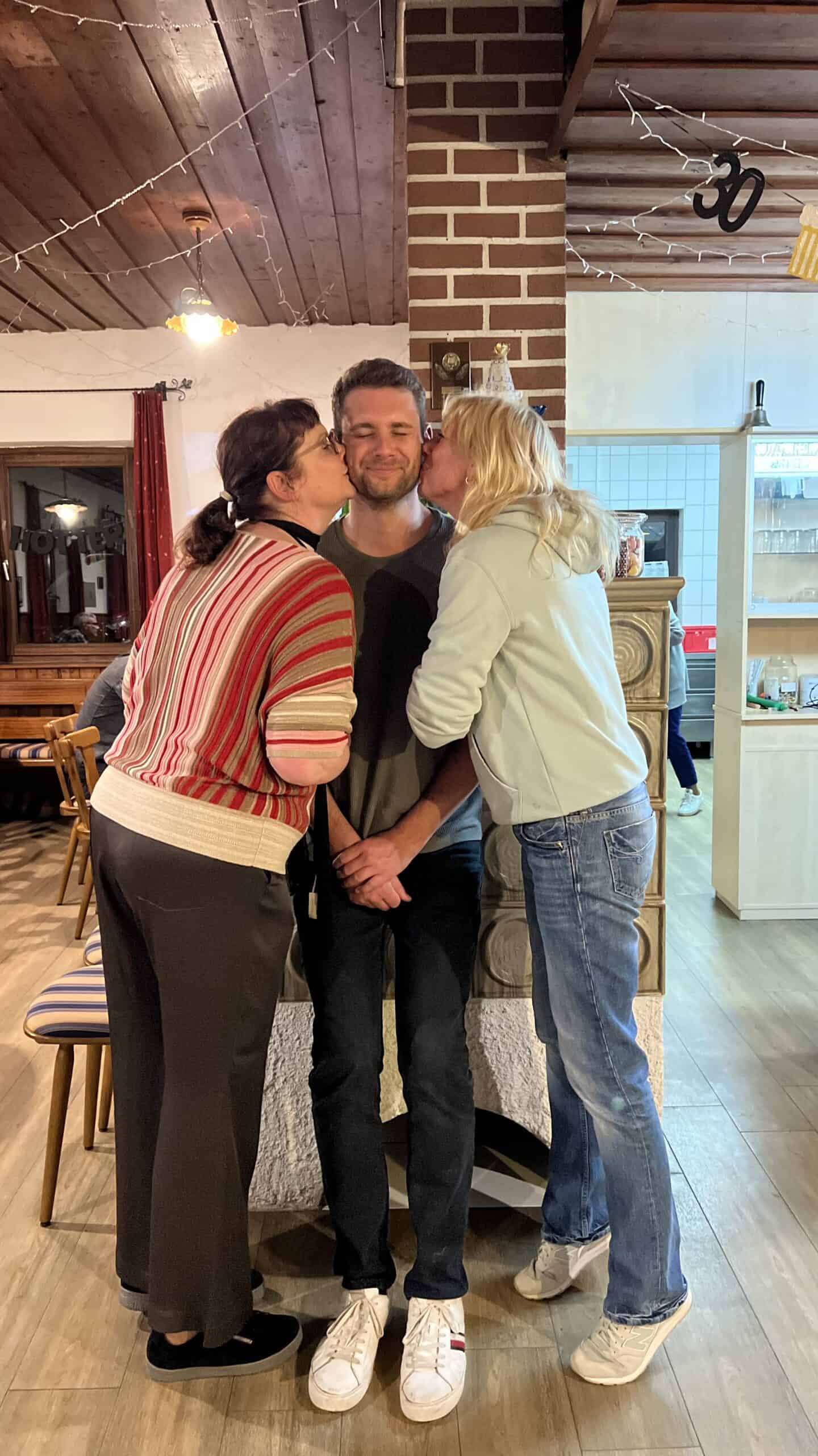 Lustige Geburtstagsfeier mit Umarmungen und Küssen, glückliches Paar in gemütlicher Atmosphäre.