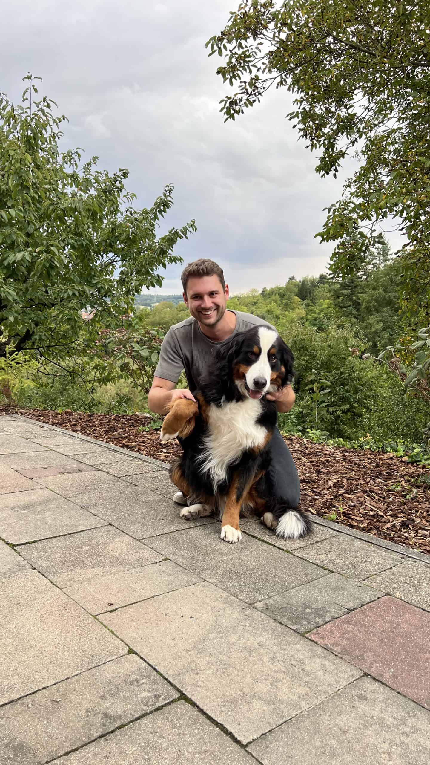 Glücklicher Mann mit Berner Sennenhund im Grünen, Geburtstagsbild, Natur, Freundschaft, 30. Geburtstag, Hundeliebe, outdoor, Feier, Freude, Sonntag, Naturerlebnis.