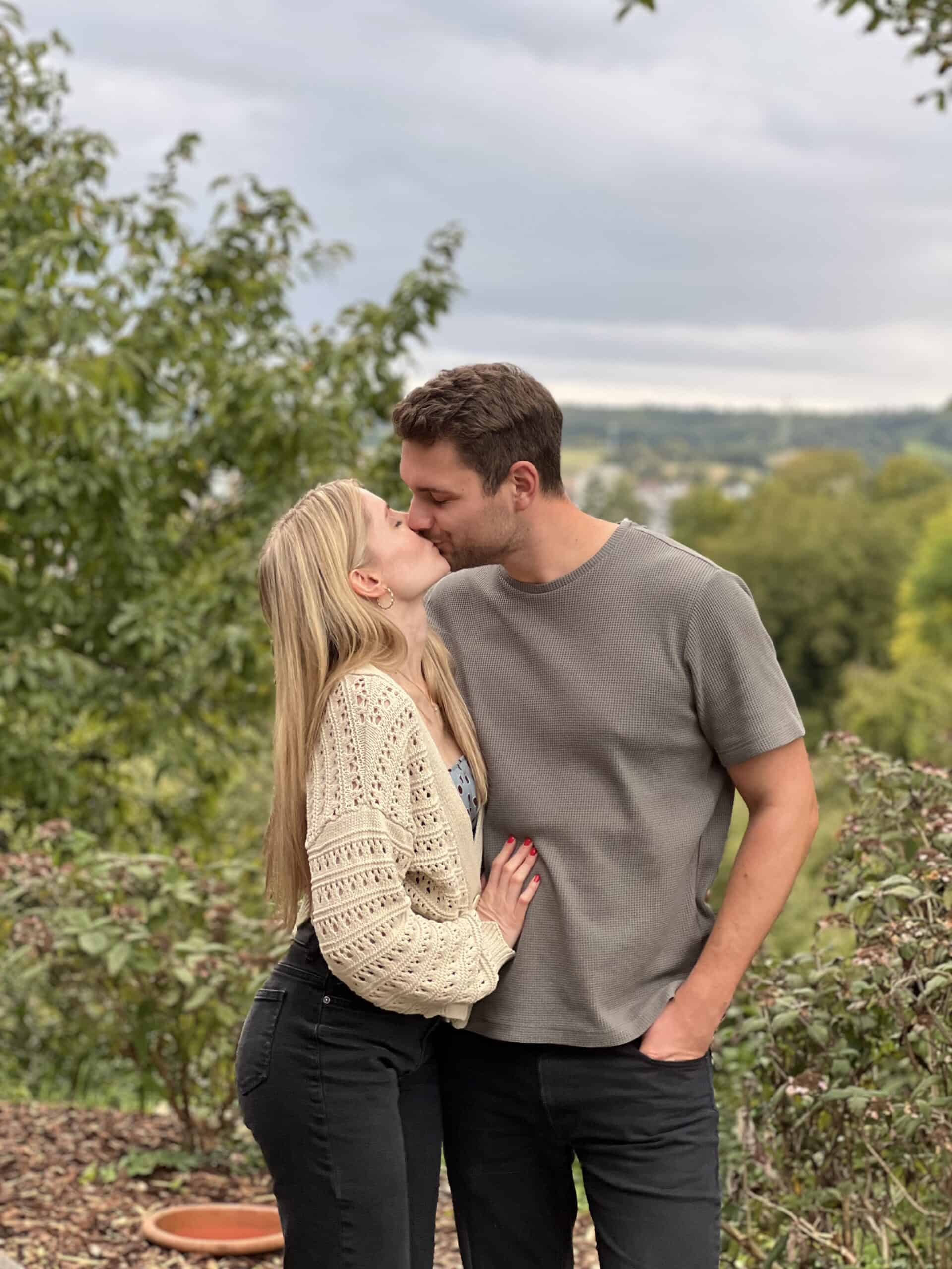 Liebespaar beim Kuss an einem sonnigen Tag im Grünen, perfekt für 30. Geburtstag.